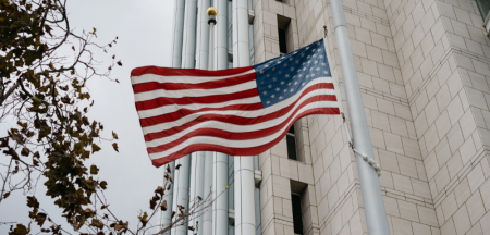 American flag with a skyscraper in the background.