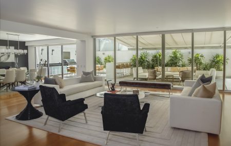 Living room and kitchen in a home with large windows and modern, sophisticated decor. as part of a virtual home tour.