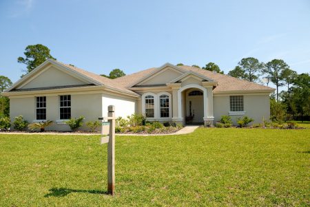 A distressed property with a for sale sign out front